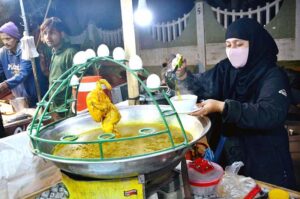 A woman vendor displaying chicken soup to attract the customers at Latifabad.