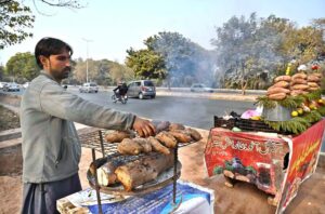 A vendor busy roasting sweet potatoes to attract the customers at his setup along Club Road.
