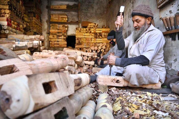 Laborers busy in making parts of traditional bed (charpai) at their workplace in the Dabgari area