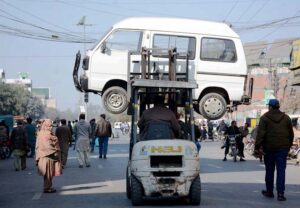 A traffic warden uses a lifter to remove an illegally parked vehicle, ensuring smooth traffic flow in the city.