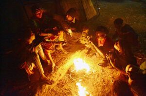 People sitting around the fire to keep them warm during chilled weather in the city.