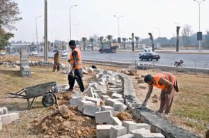 A CDA gardener waters a tree near Aabpara in the Federal Capital.