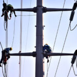 WAPDA staffers install new electricity cables on a pole to address power fluctuations and shortages in Model Town