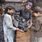 Vendors packing coal in bags for sell at their setup