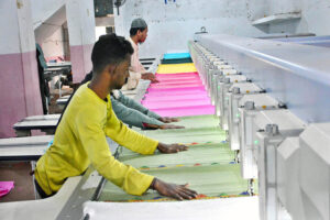 A worker is busy operating a power loom to prepare cloth in a local factory.