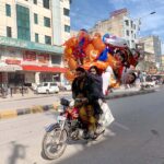 A street vendor is selling colorful balloons on his bike while roaming the streets of Gori town to attract customers in the federal capital