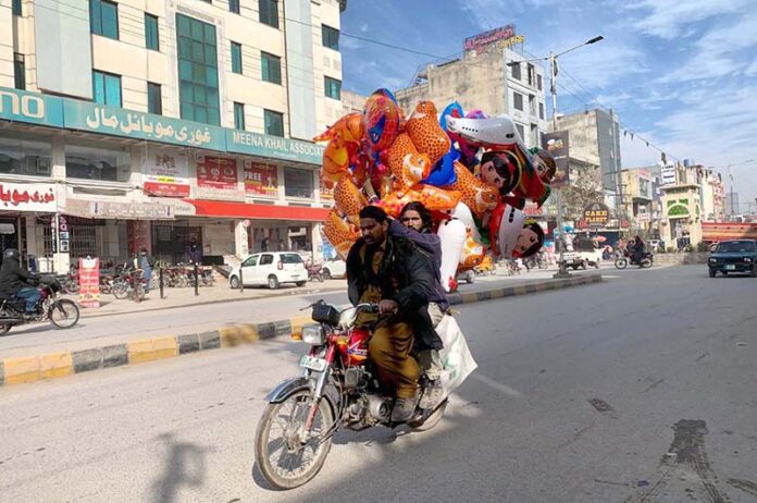 A street vendor is selling colorful balloons on his bike while roaming the streets of Gori town to attract customers in the federal capital