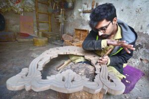 Carpenter busy in making designs on wood at his workplace in Tehsil area.