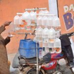 A vendor showcasing beautiful pet fish on his bicycle stand to attract customers along the roadside