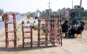 Vendor is displaying colorful wooden benches at roadside.