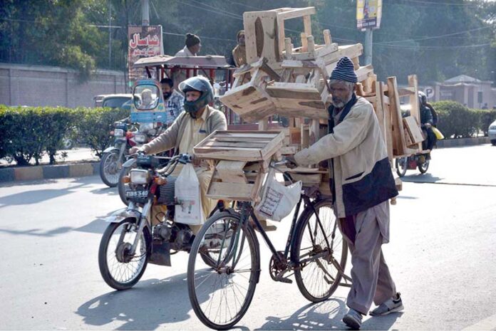 A vendor moving his bicycle loaded with wooden stools on the way going to local market