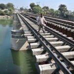 A man crossing Phuleli Canal on a railway bridge, risking a potential mishap at Tando Yousuf
