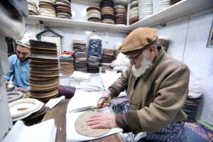 A craftsman meticulously sewing beautiful, warm traditional Chitrali caps at his setup in Jahangirpura.