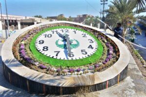 An HMC worker waters the plants around the big clock at Thandi Sarak, aiming to enhance the area's beautification.