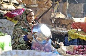 A hardworking woman earns her livelihood by selling onions, tomatoes, and other vegetables at her stall in the local vegetable market near Shadman Town.