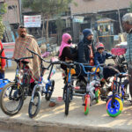 A couple selecting a bicycle for their child from a vendor at Latifabad