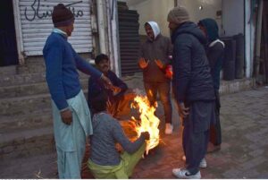 People gather around fire, to warm themselves as the temperature drops in the city.