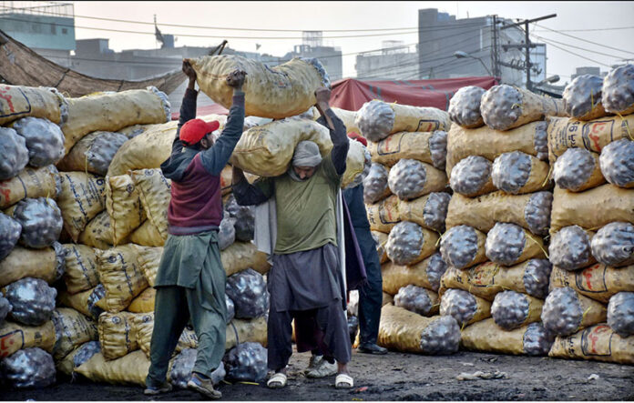 Labourers busy in loading vegetable bags in delivery truck at Sabzi Mandi