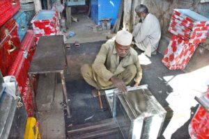 A skilled craftsman meticulously welds and assembles iron sheets, shaping them into sturdy boxes