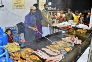 A food vendor frying fish and seafood to meet the high demand as temperatures drop in the city this winter season at Latifabad.