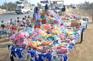 A girl selects toys for purchase from a roadside vendor in the city.