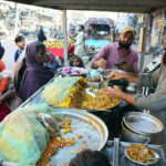 A street food vendor sells traditional, flavorful spiced chickpea snacks to women customers outside Phulile Road