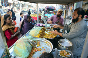 A street food vendor sells traditional, flavorful spiced chickpea snacks to women customers outside Phulile Road