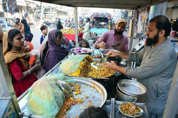 A street food vendor sells traditional, flavorful spiced chickpea snacks to women customers outside Phulile Road