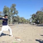 Youngsters playing traditional game along railway tracks