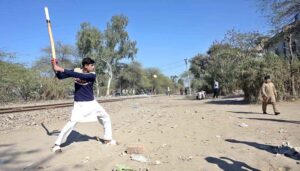 Youngsters playing traditional game along railway tracks