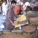 A worker is busy cleaning and sifting roasted chickpeas for customers at his workplace