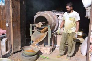 A worker busy in roasting grams for customers at his workplace.