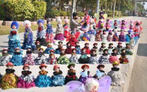 A roadside vendor displays beautiful dolls to attract customers at his setup in the city.