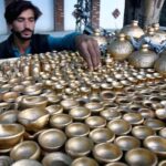 A vendor arranging and displaying the colorful handmade clay pots to attract the customers on their handcart at roadside setup in the Provincial Capital