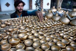 A vendor arranging and displaying the colorful handmade clay pots to attract the customers on their handcart at roadside setup in the Provincial Capital