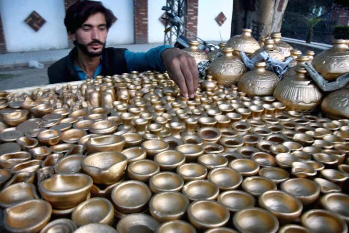 A vendor arranging and displaying the colorful handmade clay pots to attract the customers on their handcart at roadside setup in the Provincial Capital