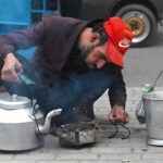 A coffee seller lights up coal to beat the bitter cold while serving customers