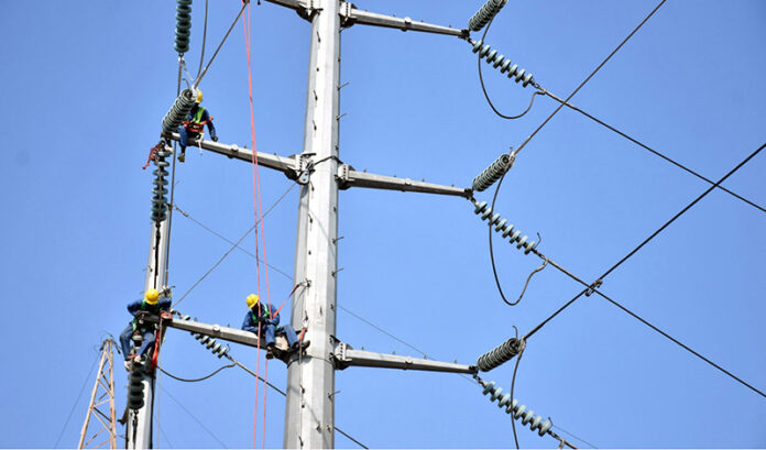 WAPDA staffers busy in installing new electricity cables on the electric pole at Ferozpur Road