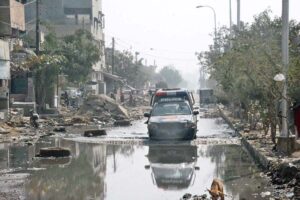 Traffic passes through the sewage-submerged road leading to Chakra Goth graveyard, highlighting poor drainage and sanitation issues, causing inconvenience to residents and traffic.