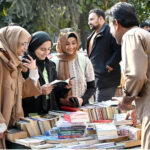 Women busy in selecting and purchasing old books from roadside stall at Mall Road