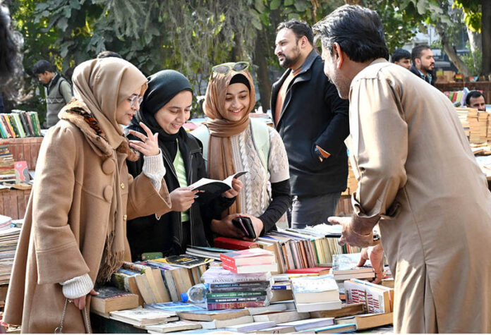 Women busy in selecting and purchasing old books from roadside stall at Mall Road