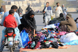 A woman selecting old warm clothes from a roadside vendor
