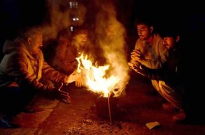 A group of people huddle around a crackling wood fire, finding warmth and comfort as the winter chill takes hold in Provincial Capital.