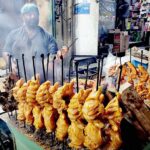 A vendor preparing traditional chicken roast for customers outside his restaurant at Railway Station Road