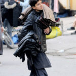 A young street vendor is displaying jackets while moving along the road at Hussain Agahi, aiming to attract customers and earn a livelihood through his sales