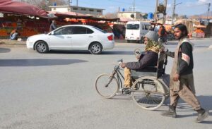 A man pushing a cycle of a special person to help him cross the Joint Road.