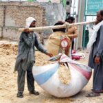 A vendor measures bundles of dried hay, essential for balanced cattle fodder, at local markets