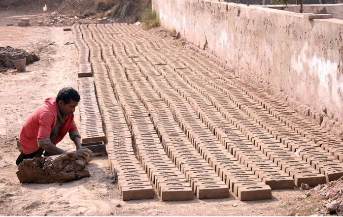 A laborer making raw bricks at a local kiln