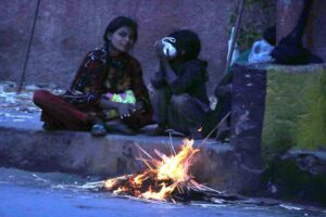 A woman with her kids sitting near the fire to keep them warm in the city at Court Road