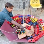 A vendor arranging and displaying children's shoes to attract the customers at Lahori Mohalla Road